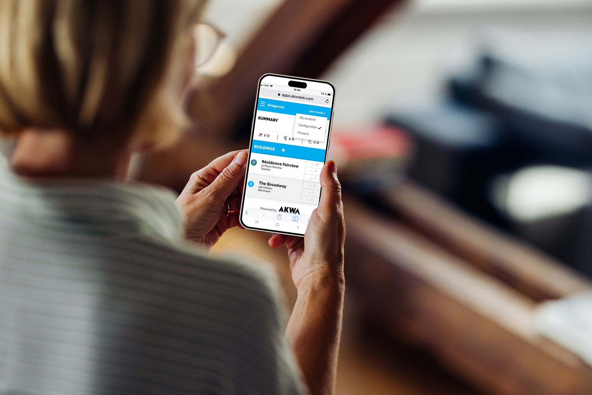 A person holding a smartphone and viewing a web page with a booking or scheduling interface, featuring a list of events or appointments. The individuals face is not visible.